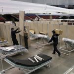 
              FILE— In this April 18, 2020 file photo partitions are installed between beds as work is performed to turn the Sleep Train Arena into a 400 bed emergency field hospital to help deal with the coronavirus, in Sacramento, Calif.  California spent nearly $200 million to set up, operate and staff alternate care sites that ultimately provided little help when the state’s worst coronavirus surge spiraled out of control last winter, forcing exhausted hospital workers to treat patients in tents and cafeterias. (AP Photo/Rich Pedroncelli, File)
            