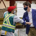 
              Canada Prime Minister Justin Trudeau elbow bumps elbows with an employee as he tours the AAA Door company in Calgary, Alberta, Wednesday, July 7, 2021. (Jeff McIntosh/The Canadian Press via AP)
            