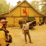 Homeowner John Gleason speaks with firefighters as the Dixie Fire approaches in Plumas County, Calif., Sunday, July 25, 2021. Officials expanded evacuation orders earlier in the day. (AP Photo/Noah Berger)