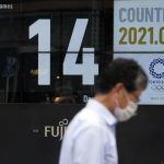 
              A man wearing a face mask walks past the countdown clock for the Tokyo 2020 Olympic Games near the Shimbashi train station Friday, July 9, 2021, in Tokyo. (AP Photo/Eugene Hoshiko)
            