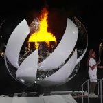 
              Naomi Osaka stands beside the Olympic flame after lighting it during the opening ceremony in the Olympic Stadium at the 2020 Summer Olympics, Friday, July 23, 2021, in Tokyo, Japan. (AP Photo/David J. Phillip)
            