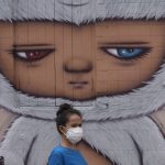 
              A woman wearing a face mask to help curb the spread the coronavirus walks past wall art in Bangkok, Thailand, Tuesday, July 20, 2021. (AP Photo/Sakchai Lalit)
            