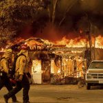 
              Firefighters pass a burning home as the Sugar Fire, part of the Beckwourth Complex Fire, tears through Doyle, Calif., on Saturday, July 10, 2021. Pushed by heavy winds, the fire came out of the hills and destroyed multiple residences in central Doyle. (AP Photo/Noah Berger)
            