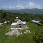 
              An aerial view shows the property of drug trafficker Nery Orlando Lopez Sanabria, where he is buried in the mausoleum, center, still under construction, after he was killed in a prison riot, in the Santa Barbara department of Honduras, Thursday, July 15, 2021. More than 1,000 people are stranded in this area marked by poverty and drug violence that have driven so many Hondurans to the United States. (AP Photo/Rodrigo Abd)
            