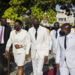 
              FILE - In this May 18, 2021 file photo, Haitian President Jovenel Moise, center, walks with first lady Martine Moise, left, and interim Prime Minister Claude Joseph, right, during a ceremony marking the 218th anniversary of the creation of the Haitian flag in Port-au-Prince, Haiti. Moïse was assassinated in an attack on his private residence early Wednesday, and the first lady was shot in the overnight attack and hospitalized, according to a statement from Joseph. (AP Photo/Joseph Odelyn, File)
            