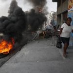 
              A woman runs past tires set on fire by protesters upset with growing violence in the Lalue neighborhood of Port-au-Prince, Haiti, Wednesday, July 14, 2021. Haitian President Jovenel Moise was assassinated on July 7. (AP Photo/Fernando Llano)
            