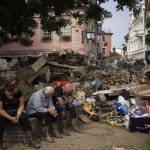 
              People rest from cleaning up the debris of the flood disaster in Bad Neuenahr-Ahrweiler, Germany, Monday July 19, 2021. More than 180 people died when heavy rainfall turned tiny streams into raging torrents across parts of western Germany and Belgium, and officials put the death toll in Ahrweiler county alone at 110. (AP Photo/Bram Janssen)
            