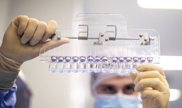 In this March 2021 photo provided by Pfizer, a technician inspects filled vials of the Pfizer-BioNT...