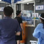 A medical worker in a booth takes a nasal sample from a man during a coronavirus testing at a makeshift testing site in Seoul, South Korea, Friday, July 16, 2021. South Korean officials are pushing for tightened pandemic restrictions beyond the hard-hit capital area as they wrestle with a record-breaking surge in coronavirus cases. (AP Photo/Ahn Young-joon)