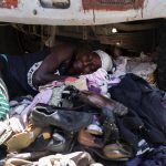 
              A vendor of used shoes and secondhand clothing sleeps under a truck in Port-au-Prince, Haiti, Saturday, July 10, 2021, three days after President Jovenel Moise was assassinated in his home. (AP Photo/Joseph Odelyn)
            