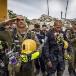 
              A member of the Israeli search and rescue team, left, salutes in front of the rubble that once was Champlain Towers South during a prayer ceremony, Wednesday, July 7, 2021, in Surfside, Fla. Members of search and rescue teams and Miami-Dade Fire rescue, along with police and workers who have been working at the site of the collapse gathered for a moment of prayer and silence next to the collapsed tower. (Jose A Iglesias/Miami Herald via AP)
            