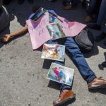 
              FILE - In this Sept. 1, 2020 file photo, a demonstrator lies on the pavement imitating the lifeless body of Bar Association President Monferrier Dorval, covered with photos of the murder scene, during a protest to demand justice for Dorval, who was fatally shot in Port-au-Prince, Haiti. On Friday, July 9, 2021, The Associated Press reported on claims circulating online wrongly asserting that a photo of a man lying on the pavement in blue pants covered in blood shows Haitian president Jovenel Moïse after his assassination early Wednesday. The photo is really from the Aug. 29, 2020, killing of Dorval, a prominent lawyer who was shot outside his home. (AP Photo/Dieu Nalio Chery, File)
            