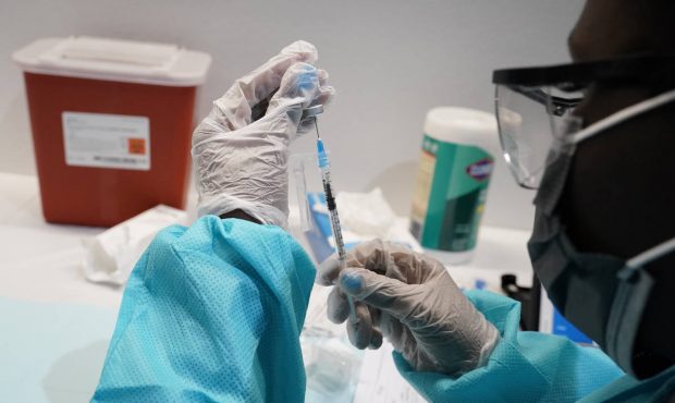 FILE - In this July 22, 2021 file photo, a health care worker fills a syringe with the Pfizer COVID...