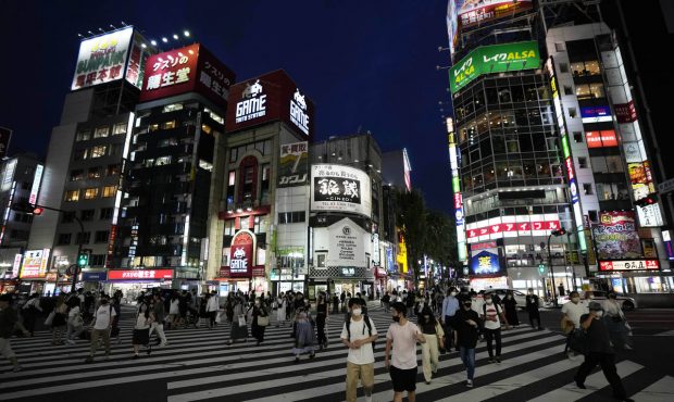 People walk along a pedestrian crossing Friday, July 30, 2021, in Tokyo, as Japanese Prime Minister...