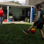 Eugenia Rodriguez, left, plays ball with her youngest son, Aaron, 6, in the backyard of her house Friday, July 2, 2021, in Chicago's Little Village neighborhood. Rodriguez hasn't been eligible for insurance coverage after overstaying a visitor visa from Mexico. She used to wake up every two or three hours at night to check on her mother. Since getting health insurance through the Illinois program, her mother has all the medications she needs. (AP Photo/Shafkat Anowar)