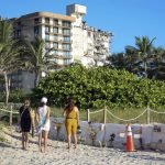 
              Daniela Valido, left, Daphnie Lucero, center, and Rebeca Salazal, right, stop at a makeshift memorial near the site of the partially collapsed South Florida condo building, Champlain Towers South, in Surfside, Fla.,  Sunday, July 4, 2021. Demolition specialists carefully bored holes Sunday to insert explosive charges into the precarious, still-standing portion of a collapsed South Florida condo building that will come down to open up new areas for rescue teams to search. Eighty percent of the drilling work was complete, and the remaining structure could come down as soon as Sunday night, Miami-Dade Assistant Fire Chief Raide Jadallah told relatives of those missing in the collapse. (Carl Juste/Miami Herald via AP)
            