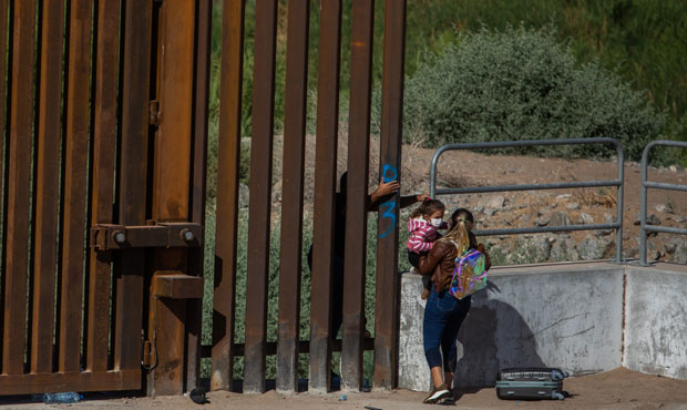 A family of asylum seekers from Cuba go around an open section of wall at the US-Mexico border to t...