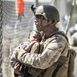 In this image provided by the U.S. Marine Corps, a Marine with Special Purpose Marine Air-Ground Task Force-Crisis Response-Central Command calms a child during an evacuation at Hamid Karzai International Airport in Kabul, Afghanistan, Thursday, Aug. 26, 2021. (Sgt. Samuel Ruiz/U.S. Marine Corps via AP)