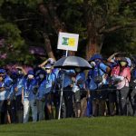 
              Volunteers wearing face masks to help curb the spread of the coronavirus hold a social distancing sign as they gather in-line to watch the final round of the men's golf event at the 2020 Summer Olympics on Sunday, Aug. 1, 2021, in Kawagoe, Japan. Japan is playing host to the Tokyo Olympics. But the capital, as well as other populous areas, are in the middle of a government-declared "state of emergency" to curb surging COVID-19 infections. (AP Photo/Andy Wong)
            