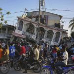 
              FILE - In this Aug. 14, 2021 file photo, residents gather outside the Petit Pas Hotel, destroyed by a 7.2 earthquake, in Les Cayes, Haiti. Haitians continue to show up at hospitals seeking care for injuries almost two weeks after an earthquake battered their country.  (AP Photo/Joseph Odelyn, File)
            