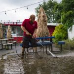 
              A worker cleans the outside area of Four Boys Ice Cream store during the passing of Tropical Storm Henri in Jamesburg, N.J., Monday, Aug. 23, 2021. (AP Photo/Eduardo Munoz Alvarez)
            