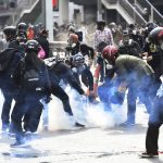 
              Anti-government protesters try to control smoke from tear gas fired by riot police during a protest in Bangkok, Thailand, Saturday, Aug. 7, 2021. Protesters demanded the resignation of Prime Minister Prayuth Chan-ocha and for part of the budget for the monarchy and the military to be redirected into the fight against the coronavirus. Many people blame Prayuth and his administration for failing to develop an adequate vaccination policy. (AP Photo/Thanachote Thanawikran)
            