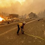 
              Battalion Chief Sergio Mora marks a road hazard as the Dixie Fire tears through the Greenville community of Plumas County, Calif., on Wednesday, Aug. 4, 2021. The fire leveled multiple historic buildings and dozens of homes in central Greenville. (AP Photo/Noah Berger)
            