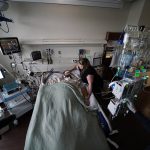 
              Lauren Debroeck, who is on oxygen as she recovers from COVID-19, talks to her husband, Michael, who also contracted COVID-19 and is being kept alive with the help of an oxygenation machine, at the Willis-Knighton Medical Center in Shreveport, La., Wednesday, Aug. 18, 2021. (AP Photo/Gerald Herbert)
            