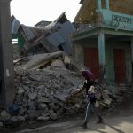 
              A woman walks past a collapsed building in Jeremie, Haiti, Wednesday, Aug. 18, 2021, four days after the city was struck by a 7.2-magnitude earthquake. (AP Photo/Matias Delacroix)
            