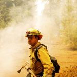 
              Firefighter Erik Padilla with Northern Sonoma County Fire District extinguishes hot spots while protecting Lake Almanor West homes from the Dixie Fire on Thursday, Aug. 5, 2021, in Plumas County, Calif. Padilla works out of the Geyserville Fire Station. (AP Photo/Noah Berger)
            