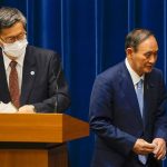 
              FILE - In this Aug. 17, 2021, file photo, Japanese Prime Minister Yoshihide Suga, right, walks past Shigeru Omi, chairman of the government's pandemic advisory panel, after a news conference at prime minister's official residence in Tokyo. Suga announced on Aug. 17, 2021, a decision to expand and extend a state-of-emergency covering Tokyo and other areas until at least mid-September, although most of the restrictions aren't legally enforceable.  (Kimimasa Mayama/Pool via AP, File)
            