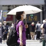 
              A woman wearing a face mask to curb the spread of the coronavirus walks with a parasol on a street in Tokyo Thursday, Aug. 5, 2021. Japan is playing host to the Tokyo Olympics. But the capital, as well as other populous areas, are in the middle of a government-declared “state of emergency” to curb surging COVID-19 infections. (AP Photo/Kantaro Komiya)
            