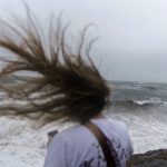 
              Strong surf from Tropical Storm Henri breaks along the Cliff Walk as a woman's hair blows in the wind in Newport, R.I., Sunday, Aug. 22, 2021. (AP Photo/David Goldman)
            