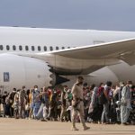 
              Afghan people who were transported from Afghanistan, walk after disembarking a plane, at the Torrejon military base as part of the evacuation process in Madrid, Monday. Aug. 23, 2021. (AP Photo/Andrea Comas)
            