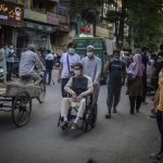 
              An Afghan refugee pushes a wheelchair through a market in New Delhi, India on Aug. 17, 2021. For thousands of Afghan refugees living in India, their plans to someday return home were dashed by the Taliban's shockingly swift takeover of the country. Some refugees struggle to put food on the table. Others are trapped in a complex bureaucratic process to register as refugees. What many thought would be a short, temporary escape has turned into a never-ending exile. (AP Photo/Altaf Qadri)
            