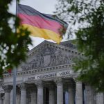 
              The German national flag waves in front of the German parliament building, the Reichstag Building, with the slogan: 'To The German People' in Berlin, Tuesday, Sept. 28, 2021. Germany's newly elected lawmakers are holding their first meetings as their parties digest the fallout of the election that reduced outgoing Chancellor Angela Merkel's bloc to its worst-ever result and start the process of putting together a new government. (AP Photo/Markus Schreiber)
            