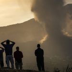 
              Residents look from a hill as lava continues to flow from an erupted volcano, on the island of La Palma in the Canaries, Spain, Friday, Sept. 24, 2021. A volcano in Spain’s Canary Islands continues to produce explosions and spew out lava, five days after it erupted. Two rivers of lava continue to slide slowly down the hillside of La Palma on Friday. (AP Photo/Emilio Morenatti)
            