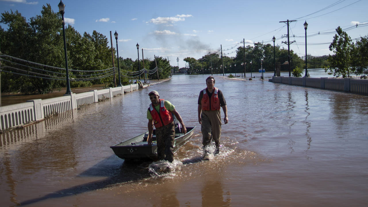 United States Geological Survey workers push a boat as they look for residents on a flooded street ...