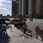 
              A man walks through a quiet Evergrande city plaza past a map showing Evergrande development projects and its apartment buildings in Beijing, Tuesday, Sept. 21, 2021. Global investors are watching nervously as the Evergrande Group, one of China's biggest real estate developers, struggles to avoid defaulting on tens of billions of dollars of debt, fueling fears of possible wider shock waves for the Chinese financial system. (AP Photo/Andy Wong)
            