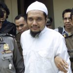 
              FILE - Militant cleric Abu Rusdan, center, is escorted by security officers after his trial hearing at a district court in Jakarta, Indonesia, in this Monday, Nov. 3, 2003 file photo. Indonesia's elite counterterrorism squad has arrested the convicted militant and suspected leader of an al-Qaida-linked group that has been blamed for a string of past bombings in the country, Indonesia police said Monday, Sept. 13, 2021. (AP Photo/Tatan Syuflana, File)
            