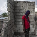 
              A gang member, wearing a balaclava and holding a gun, poses for a photo in the Portail Leogane neighborhood of Port-au-Prince, Haiti, Thursday, Sept. 16, 2021. There could be as many as 100 gangs in Port-au-Prince; no one has an exact count and allegiances often are violently fluid. (AP Photo/Rodrigo Abd)
            