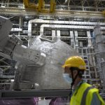 
              A worker walks past a vacuum vessel component of the ITER machine in Saint-Paul-Lez-Durance, France, Thursday, Sept. 9, 2021. Scientists at the International Thermonuclear Experimental Reactor in southern France took delivery of the first part of a massive magnet so strong its American manufacturer claims it can lift an aircraft carrier. (AP Photo/Daniel Cole)
            