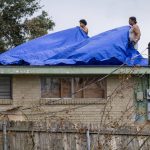 
              Men cover a roof with tarps, Monday, Sept. 6, 2021, a week after Hurricane Ida swept through the area. (Chris Granger/The Times-Picayune/The New Orleans Advocate via AP)
            