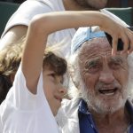 
              FILE - In this June 8, 2018 file photo, a child takes a selfie with French actor Jean-Paul Belmondo during the semifinal match at the French Open tennis tournament between Spain's Rafael Nadal and Argentina's Juan Martin Del Potro at the Roland Garros stadium in Paris. French New Wave actor Jean-Paul Belmondo has died, according to his lawyer’s office on Monday Sept. 6, 2021. (AP Photo/Alessandra Tarantino, File)
            