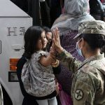 
              FILE - In this Monday, Aug. 30, 2021, file photo, Army Pfc. Kimberly Hernandez gives a high-five to a girl evacuated from Kabul, Afghanistan, before boarding a bus after they arrived at Washington Dulles International Airport, in Chantilly, Va. U.S. religious groups of many faiths are gearing up to assist the thousands of incoming refugees. (AP Photo/Jose Luis Magana, File)
            