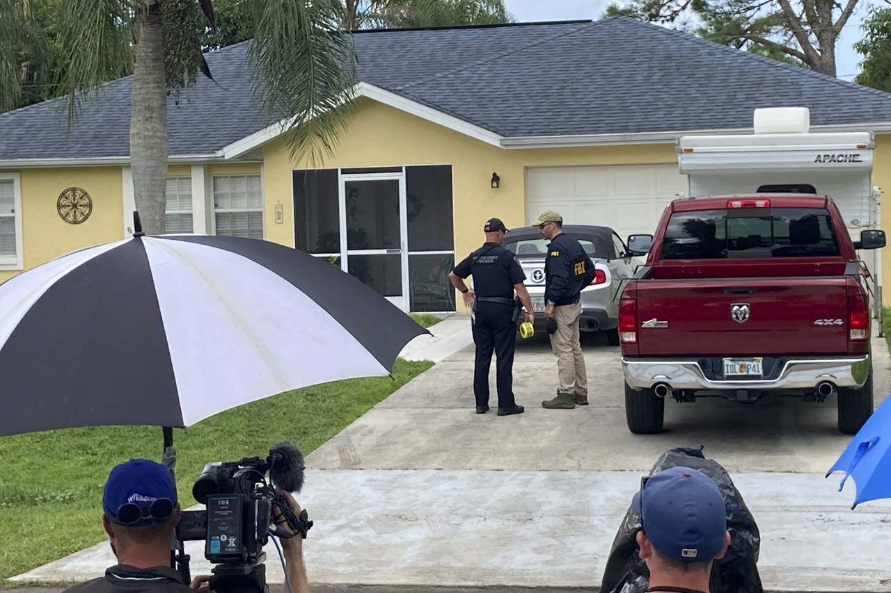 Law enforcement officials investigate home of a young man wanted for questioning in the disappearan...