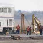 Workers stand near a train car, Monday, Sept. 27, 2021, from an Amtrak train that derailed Saturday, near Joplin, Mont., killing three people and injuring others. Federal investigators are seeking the cause of the derailment. (AP Photo/Ted S. Warren)