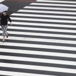 A woman wearing a face mask to help curb the spread of the coronavirus walks across an intersection in a drizzle in Tokyo, Thursday, Sept. 2, 2021. (AP Photo/Hiro Komae)