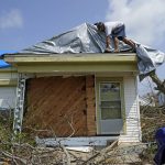 
              Gary Johnston works to put a tarp on the roof his mother-in-laws damaged home in the aftermath of Hurricane Ida, Thursday, Sept. 2, 2021, in Golden Meadow, La. (AP Photo/David J. Phillip)
            