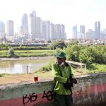 
              A municipal worker takes a break as the hazy city skyline is seen in the background in Jakarta, Indonesia, Thursday, Sept. 16, 2021. An Indonesian court ruled Thursday that President Joko Widodo and six other top officials have neglected to fulfill citizens' rights to clean air and ordered them to improve the poor air quality in the capital. (AP Photo/Tatan Syuflana)
            